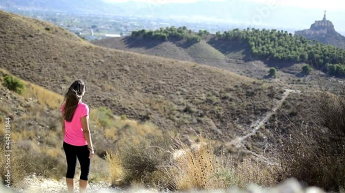 Woman hiking at mountain top against the cityscape of Murcia at sunset. photo