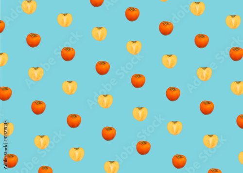 Fototapeta Naklejka Na Ścianę i Meble -  fresh pattern made with small yelow illuminating and orange kaki apple on blue background. Creative flying fruits in heart-shaped. Valentines day pattern