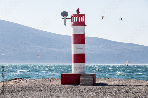 Lighthouse at the Cape. Striped red and white beacon at the seashore.