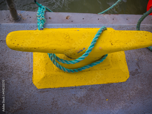 Obraz na plátně Large mooring cleat on a barge holds a line to a small boat