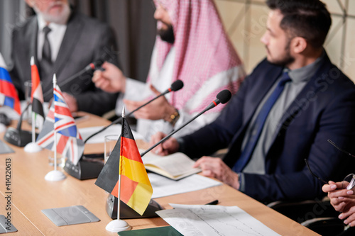 focus on german table flag while meeting, close-up photo. cropped executive people sitting at press conference, meeting without ties photo