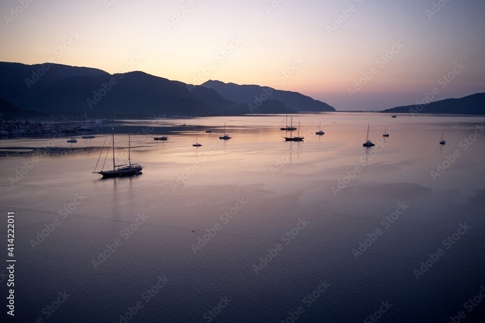 Scenic sunset view with boats on the sea. Mountains and sky in the background. Beautiful marine scene.