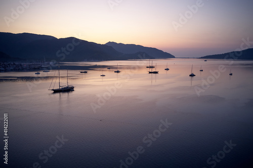 Scenic sunset view with boats on the sea. Mountains and sky in the background. Beautiful marine scene.