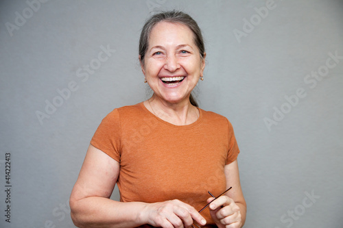 Elderly laughing woman posing on  gray background