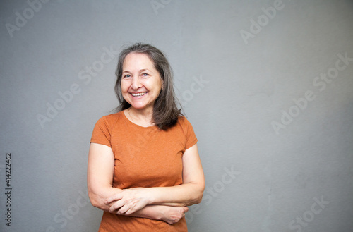 Senior woman in  brown t-shirt studio isolated on grey wall