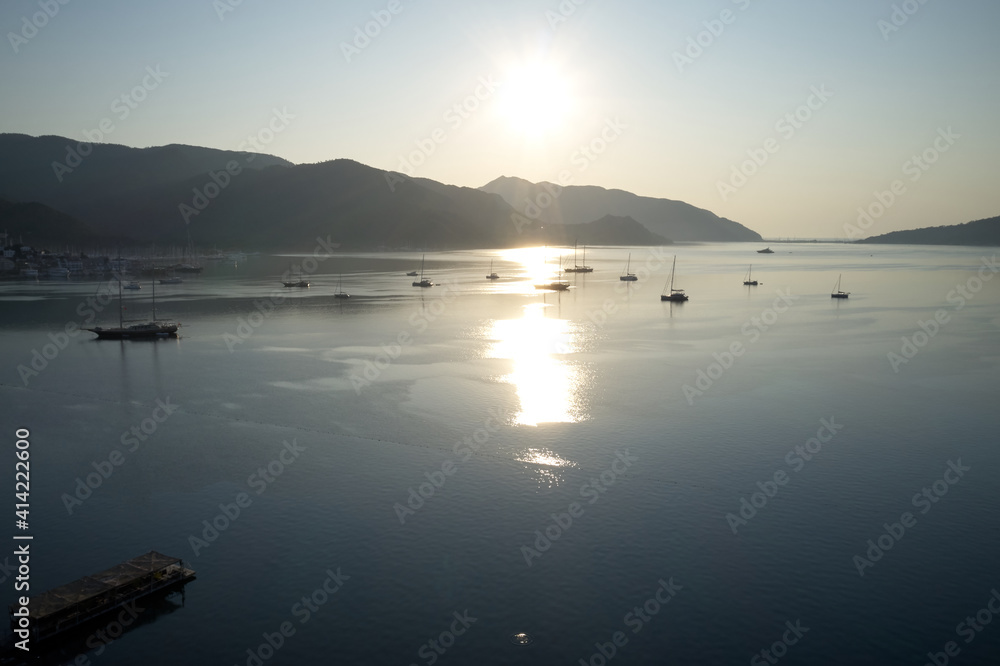 Beautiful view of sea bay with yachts in the morning. Reflection of sunlight in the water. Mountains in the background. Marmaris, Turkey.