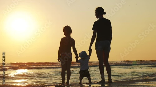 Wallpaper Mural Happy family mother with two children on vacation at the beach. Silhouette mother with two children in the sea at sunset. Torontodigital.ca