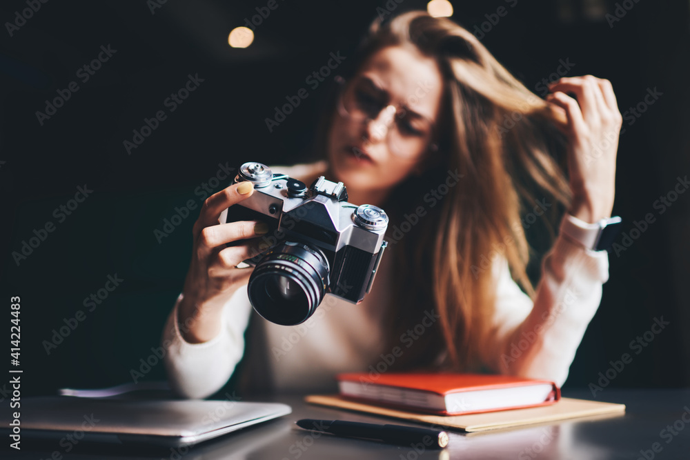 Young woman with analog photo camera at table - obrazy, fototapety, plakaty 