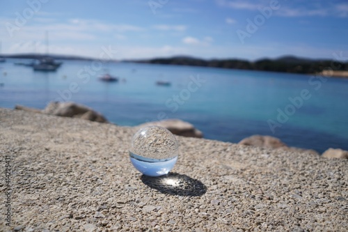 Glaskugel liegt auf einem Felsen am Meer