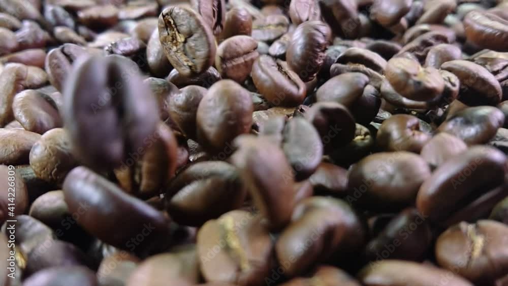 Super close-up of falling roasted coffee beans on the coffee texture in slow motion Super close-up of falling roasted coffee beans on the coffee texture in slow motion