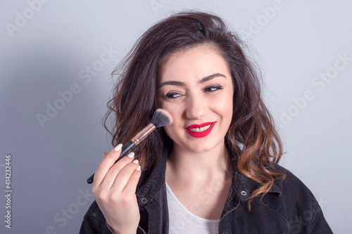 Beautiful young woman holding makeup brushes