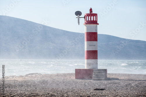 Lighthouse at the Cape. Striped red and white beacon at the seashore.