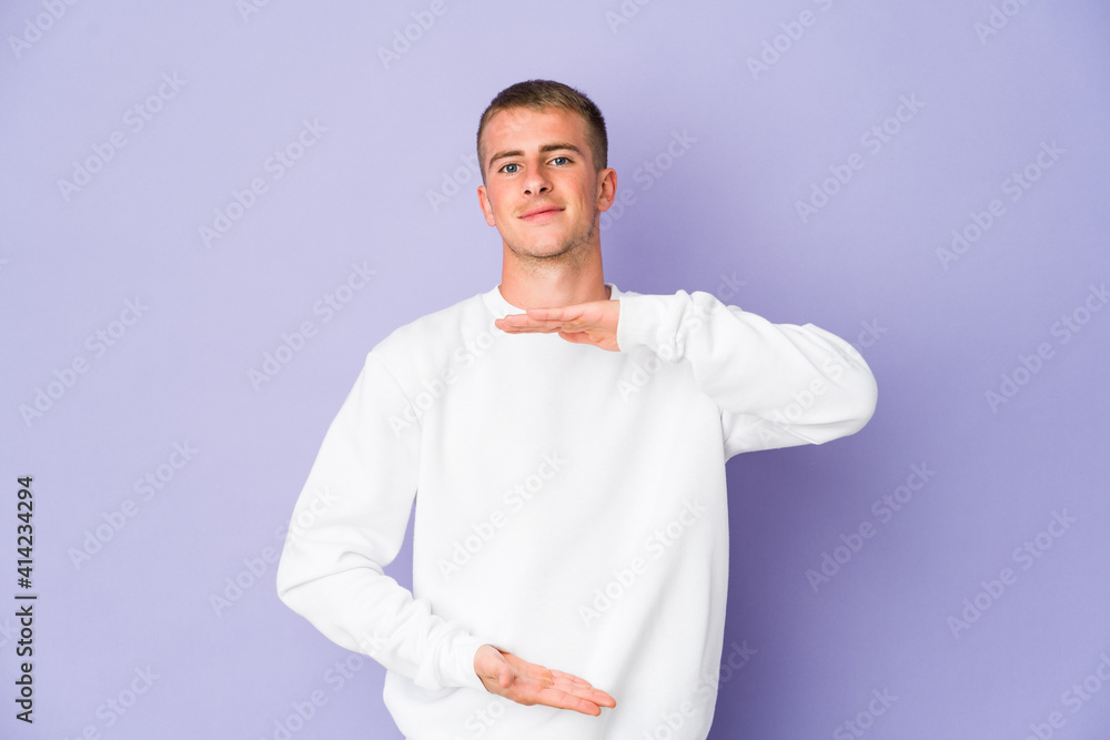 Young caucasian handsome man holding something with both hands, product presentation.