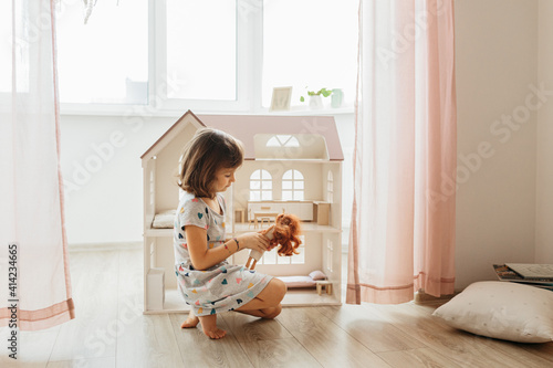 Obraz na plátně Girl playing with doll house