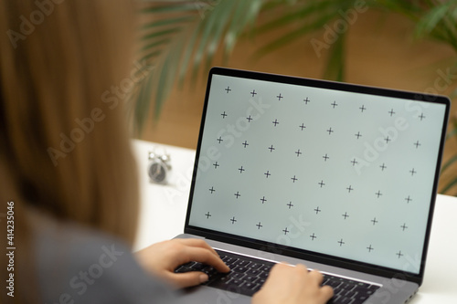 Young beautiful women with long hair working from laptop on her white office table, small clock with green plants in the background