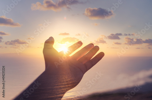 Hand reaching out to sky, touching warm sunshine finger tips. 