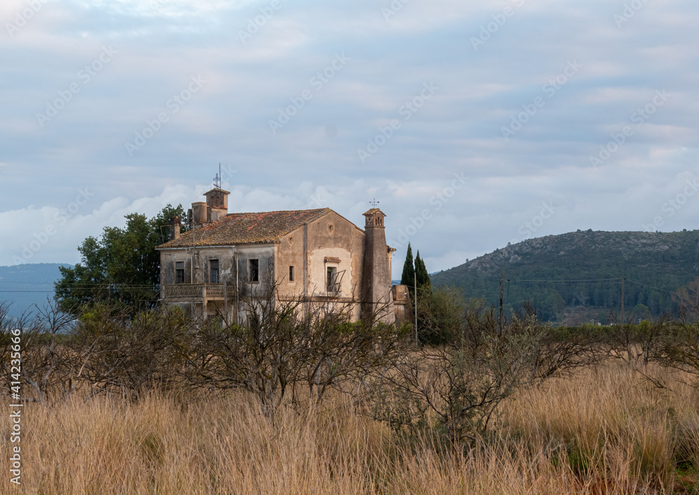 Old country house, with mountains in the background and a cloudy sky at dusk