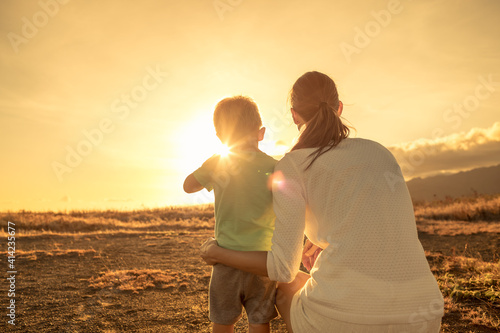 Happy mother and son on an adventure outdoors in nature feeling free facing a beautiful sunset