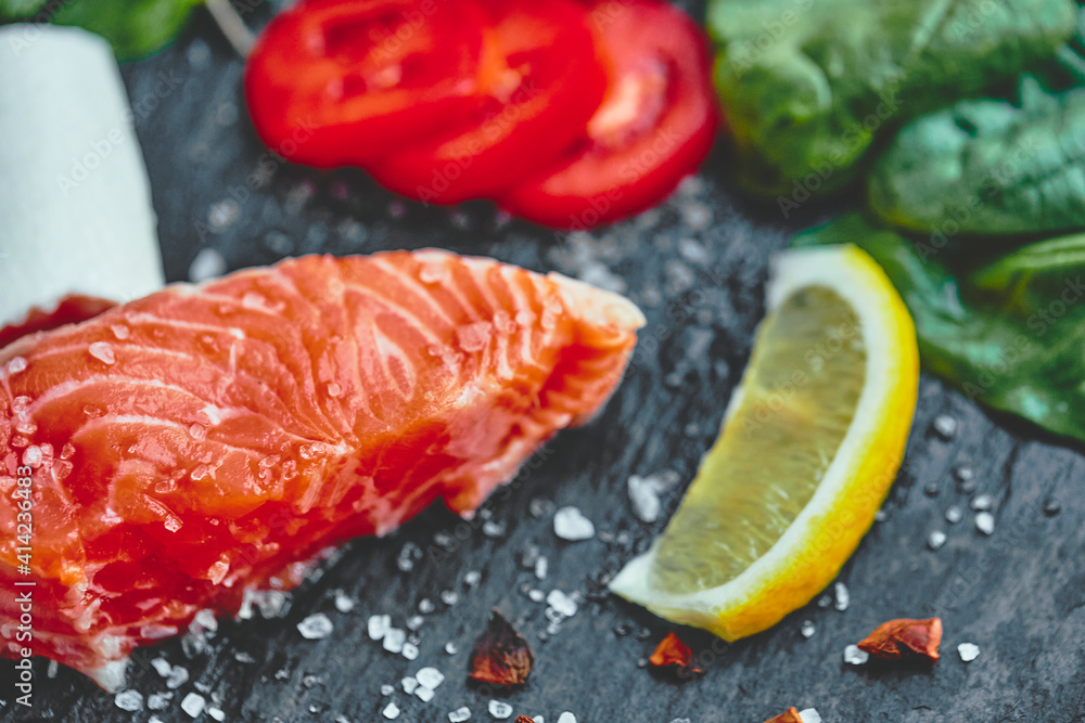 Raw salmon fillet and ingredients for cooking on a dark background. Raw salmon fillet and ingredients for cooking on a dark background.