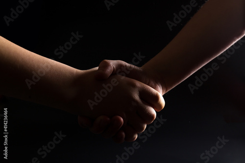 Handshake of children's hands. Shadow business. In an unspoken agreement. good deal. Silhouettes of hands on a black background.
