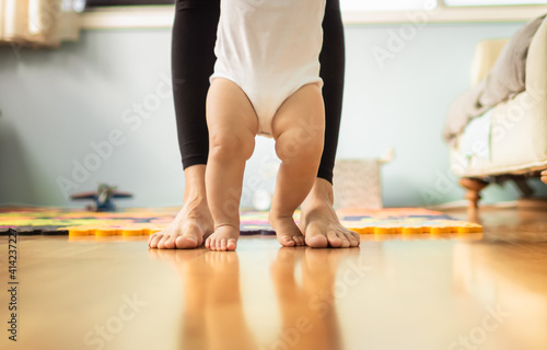 Baby learning to walk with the help of mother. Baby's first steps concept. 