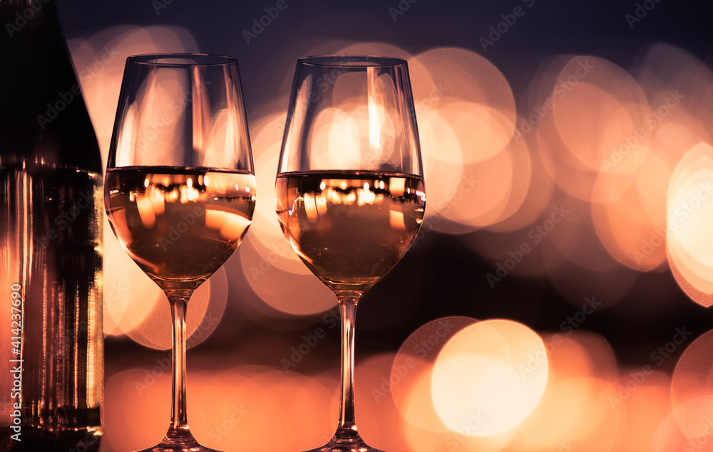 Pair of wine glasses on table and blurred city lights 