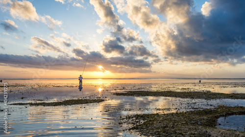 Tablou pe pânză Tiny countryman standing in the sea and fishing on background of mesmerizing clo