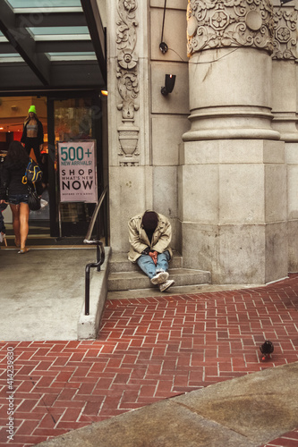 Photography Homeless man sitting outside a luxury shopping mall as people walk by, San Franc