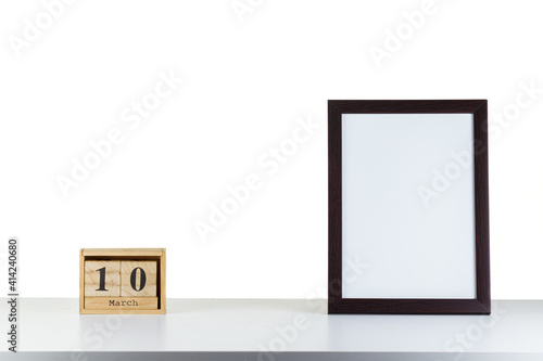 Wooden calendar 10 march with frame for photo on white table and background