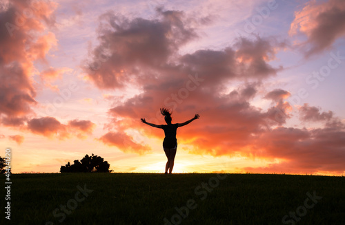 Woman feeling happy with arms up to the sunset jumping for joy.