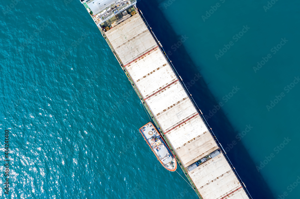 Aerial shot of a cargo ship approaching port with help of towing ship Aerial shot of a cargo ship approaching port with help of towing ship