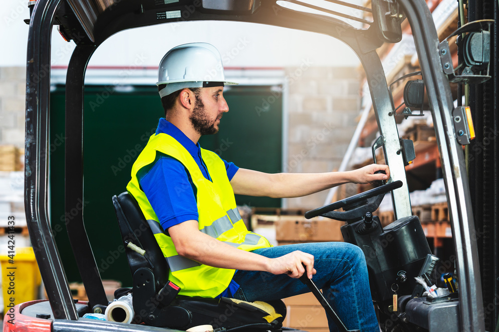 custom made wallpaper toronto digitalCaucasian male in a uniform and helmet driving the forklift through a storage room in a factory