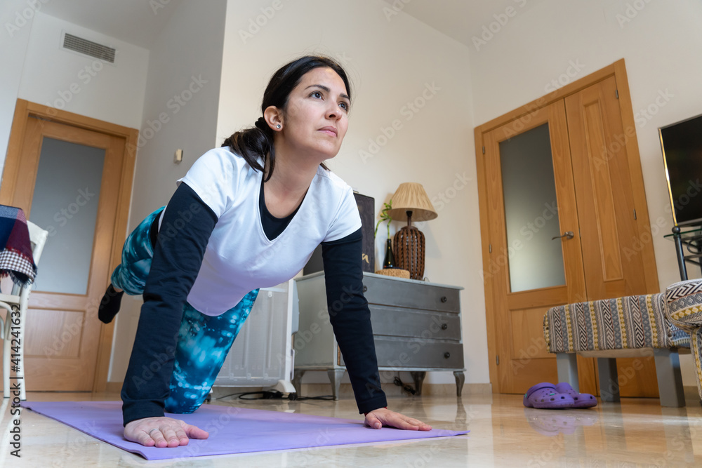 Stock photo of adult woman wearing sports clothes doing body work out in her living room. Stock photo of adult woman wearing sports clothes doing body work out in her living room.