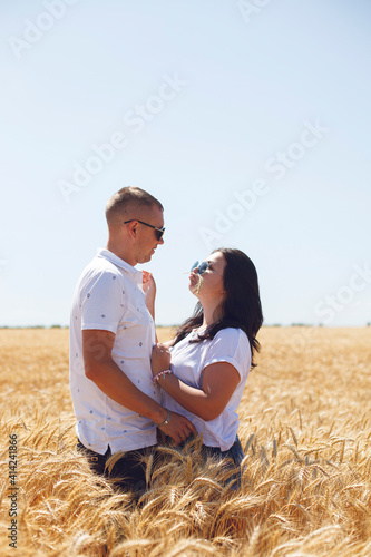 young couple in white t-shirts guy and girl look at each other in a yellow gold wheat field