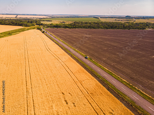 Aerial view of a grey asphalted narrow country road.