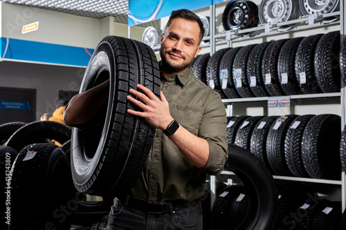 customer tire fitting in the car service, auto mechanic checks the tire and rubber tread for safety, concept: repair of machines, fault diagnosis, repair. man buy in car service shop
