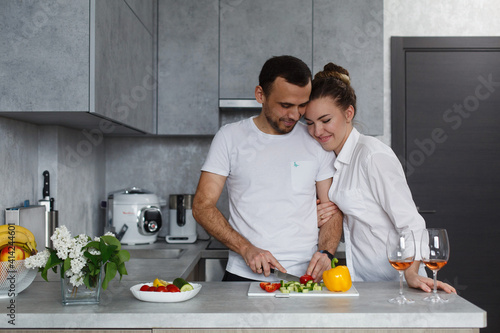 young couple in love cooking together in the kitchen. happy smiling man and woman preparing dinner at home. romantic couple in love preparing food. Young couple making breakfast