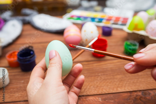 A woman with a tassel paints Easter eggs. Preparing decorations for Easter, creativity with children, traditional symbols. Preparing for Easter