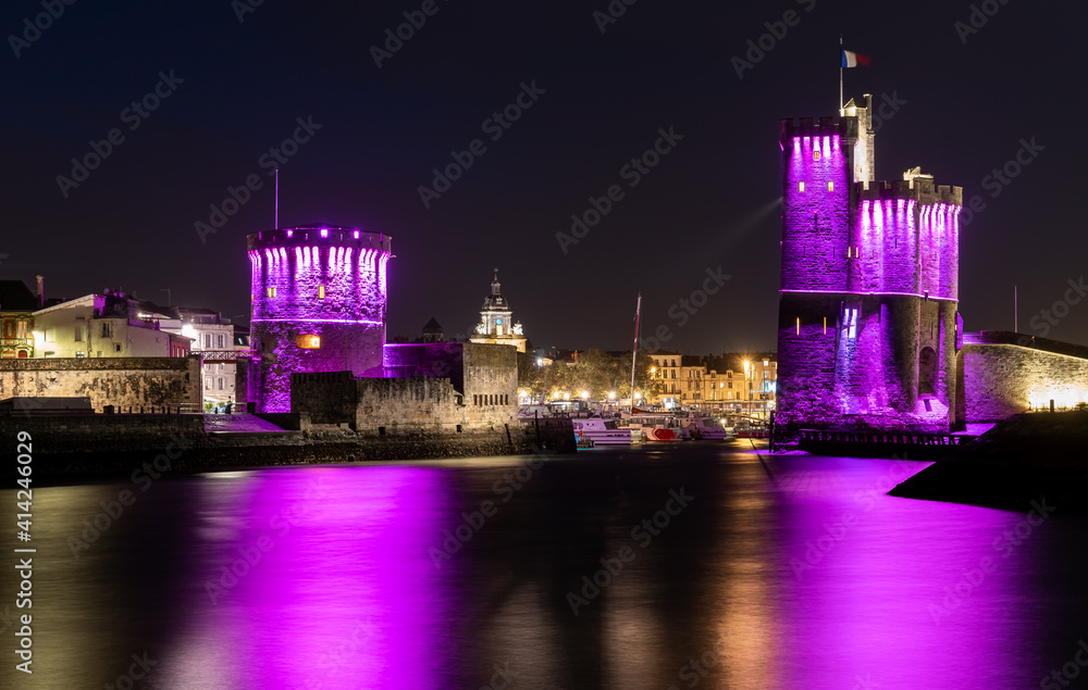 beautiful view of the old harbor of La Rochelle with its famous towers. night shot with pink lights for pink october. Pink October is breast cancer awareness month beautiful view of the old harbor of La Rochelle with its famous towers. night shot with pink lights for pink october. Pink October is breast cancer awareness month