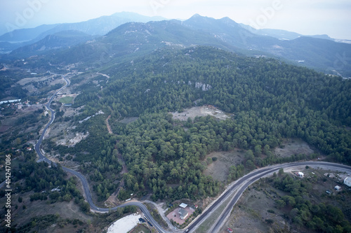 Aerial view of the mountains landscape in the morning. Road and green mountain forest. View from above.