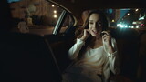 Smiling business lady flirting on smartphone in dark salon of business car.