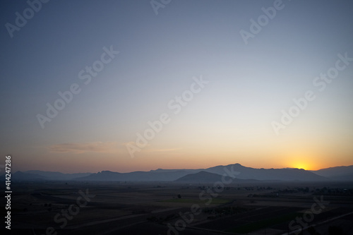 Aerial view of mountain valley at sunset. Summer farmland under sunset or sunrise sky and fog. A foggy evening on a picturesque meadow.