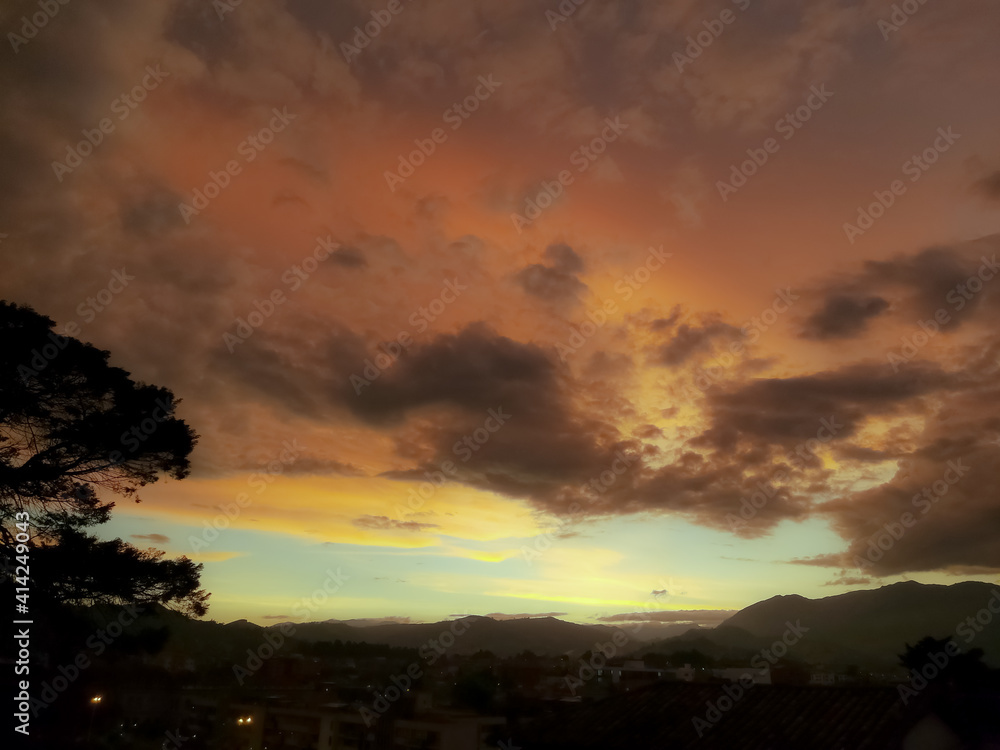 Panoramic view of a city or town during sunset. Sky in orange and blue tones.