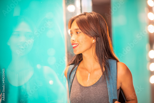 Beautiful asian woman dressed sporty going out for shopping, face reflected in the shop showcase glass