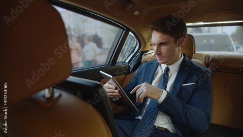 Annoyed businessman seeing bad news on tablet computer in luxury business car. © stockbusters