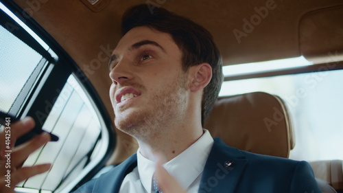 Obraz na plátně Friendly male professional dictating voice recording on phone in business car