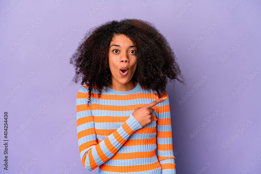 Young african american curly woman isolated on purple background pointing to the side Young african american curly woman isolated on purple background pointing to the side
