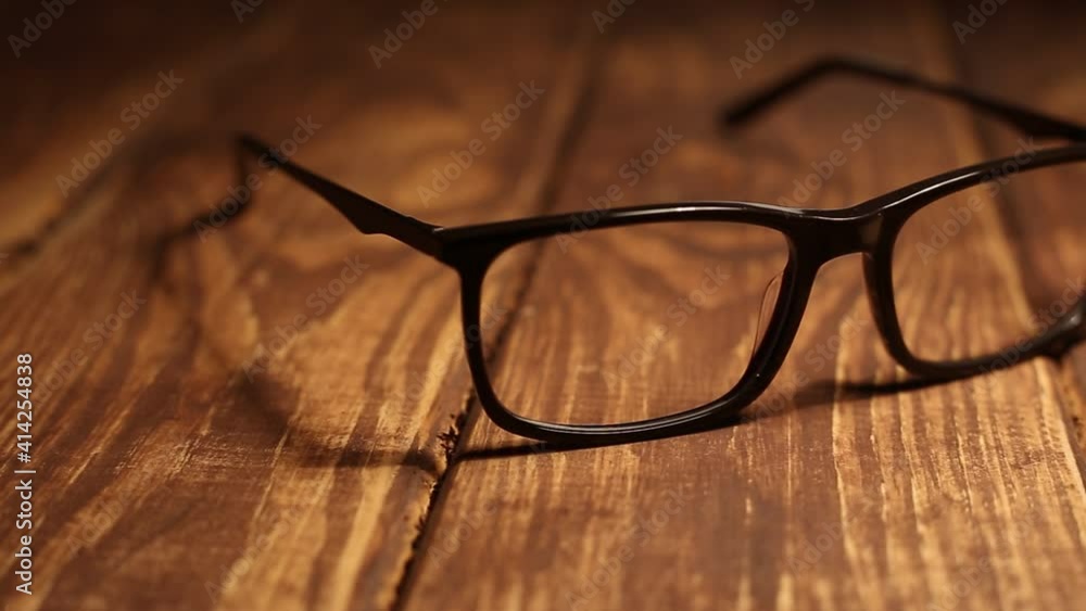 Glasses for sight lie on a wooden table. The camera panning horizontally Glasses for sight lie on a wooden table. The camera panning horizontally