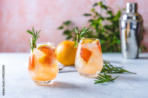 Tequila cocktail or cold lemonade with grapefruit juice, tinted with the aroma of a fresh sprig of rosemary