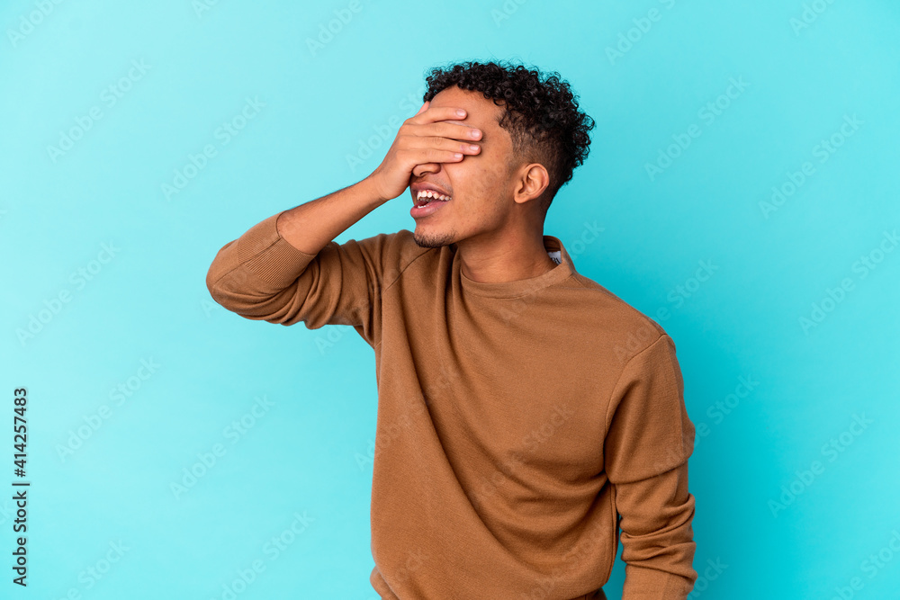 Young african american curly man isolated on blue covers eyes with hands, smiles broadly waiting for a surprise. Young african american curly man isolated on blue covers eyes with hands, smiles broadly waiting for a surprise.